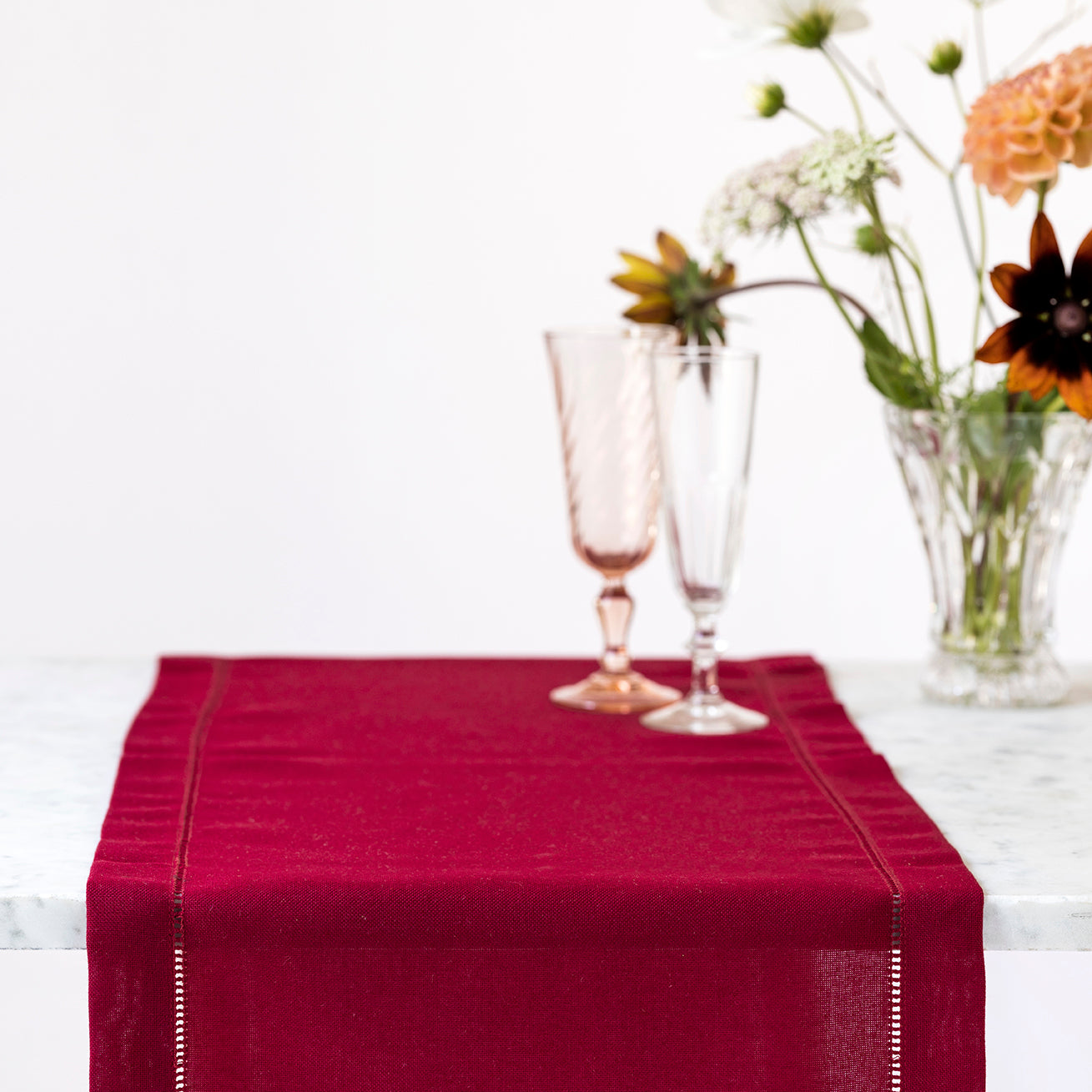 Mørkerød bordløber med broderet hulsøm